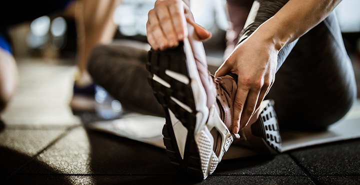 Close up of unrecognizable woman feeling pain in her ankle at gym.